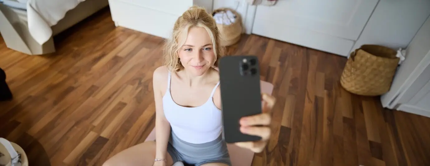 Junger sportlicher Fitness-Trainer und Yoga-Lehrer streamt live und macht dabei Selfies mit dem Smartphone.
